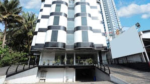 A modern building with a unique architectural design featuring cylindrical and rectangular elements. - Capital O 10611 Hotel Malabar Illam (Kanayannur)
