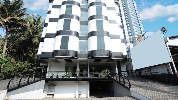 A modern building with a unique architectural design featuring cylindrical and rectangular elements. - Capital O 10611 Hotel Malabar Illam (Kanayannur)