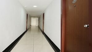 A long, narrow hallway with a wooden door on the right, marked with the number 302. - Capital O 10611 Hotel Malabar Illam (Kanayannur)