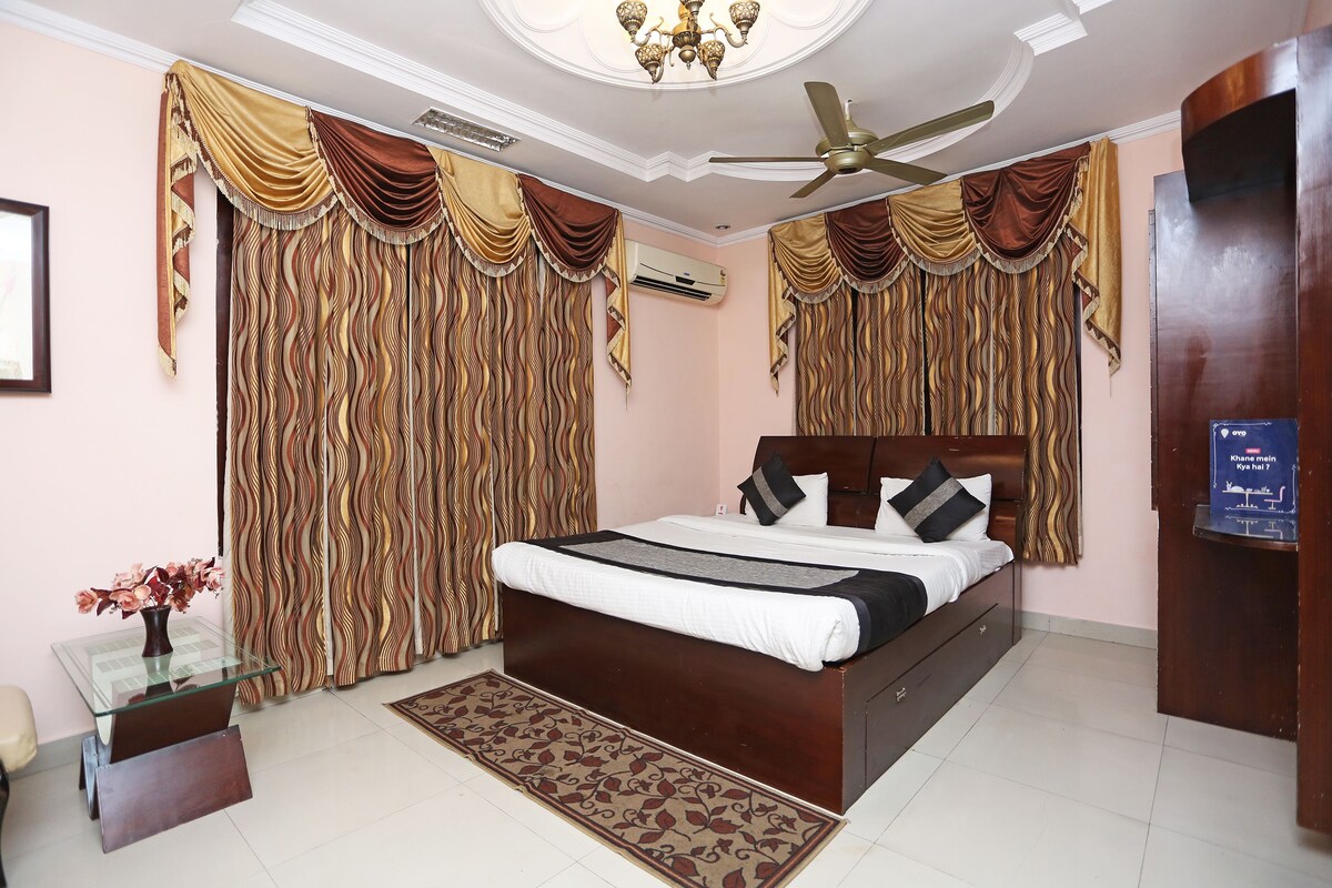 A bedroom with a large bed, a ceiling fan, and curtains.