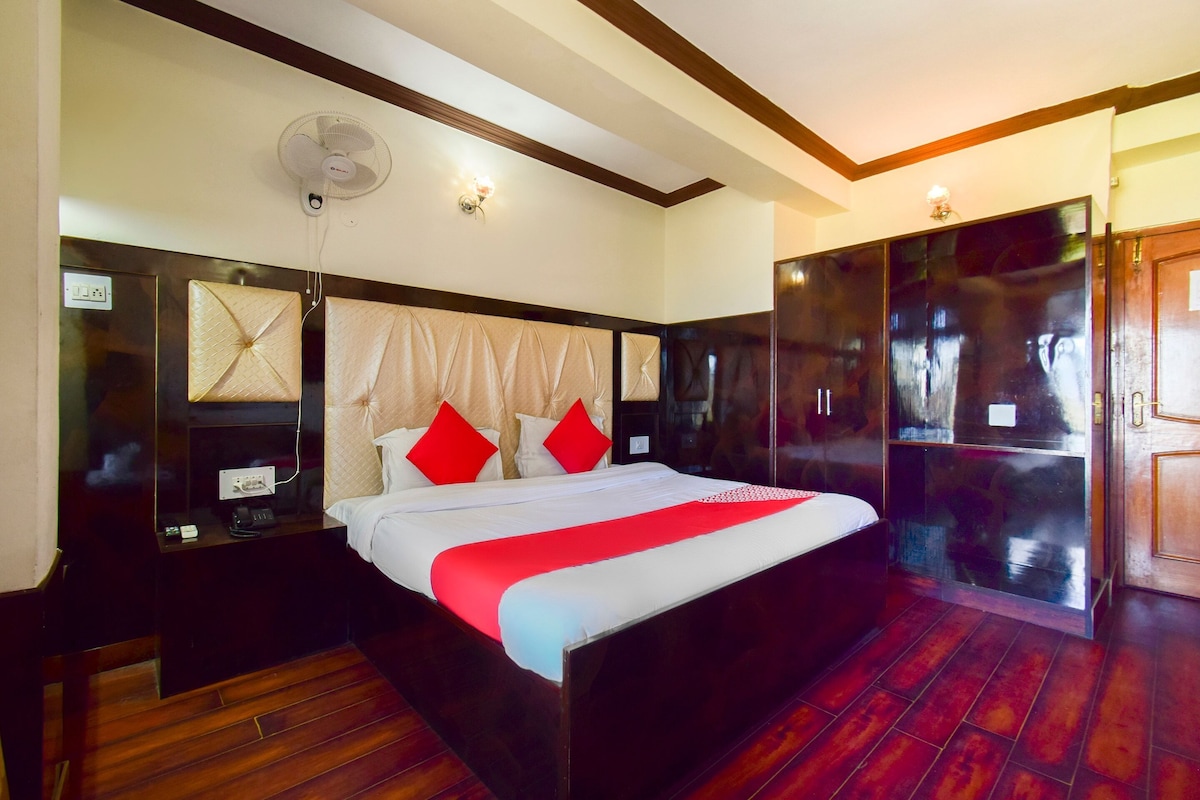 A hotel room with a large bed, a bedside table, a wardrobe, and a ceiling fan.