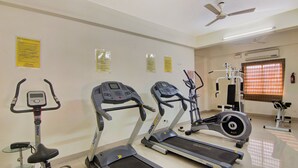Un gimnasio con cintas de correr, elípticas y una bicicleta estática.