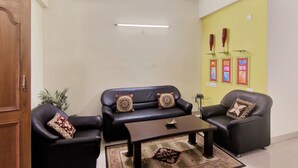 Una sala de estar con un sofá, dos sillones, una mesa de centro y una alfombra pequeña.