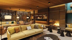 Ein modernes Wohnzimmer mit einer Couch, Sesseln und einem Couchtisch. Im Hintergrund befindet sich ein Kamin und eine Rezeption.