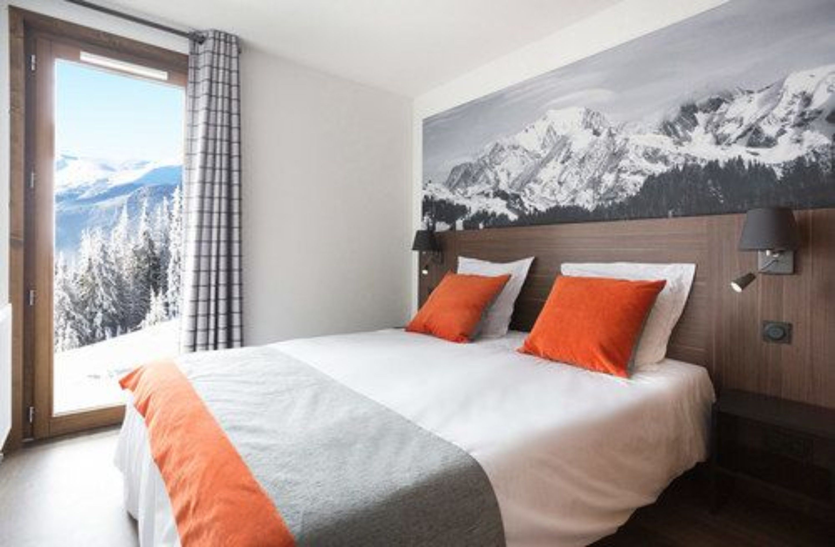 Habitación de hotel con cama, vista a la montaña y un ventanal con cortinas.