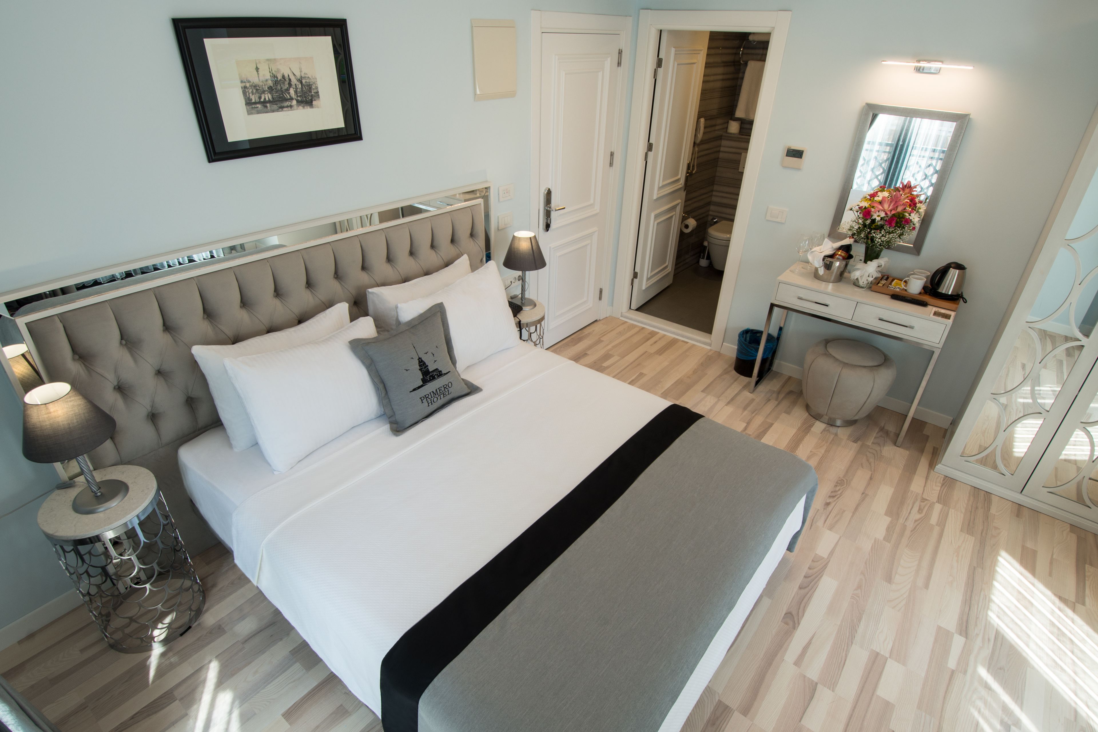 Een keurig opgemaakt slaapkamer met een groot bed, nachtkastjes, een dressoir en een spiegel.