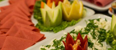 A buffet with various food items including sliced meats, vegetables, and garnishes.
