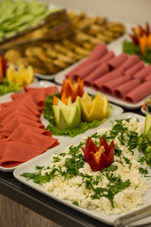 Un bufé con diversos alimentos, incluyendo carnes en rodajas, verduras y guarniciones.