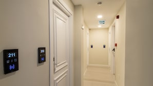 A hotel hallway with a digital door lock displaying room number 211, a digital lock for room 212, and a sign indicating the exit.