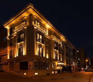 Un edificio histórico con detalles arquitectónicos ornamentales, amplias ventanas y un espacio comercial en la planta baja con señalización.
