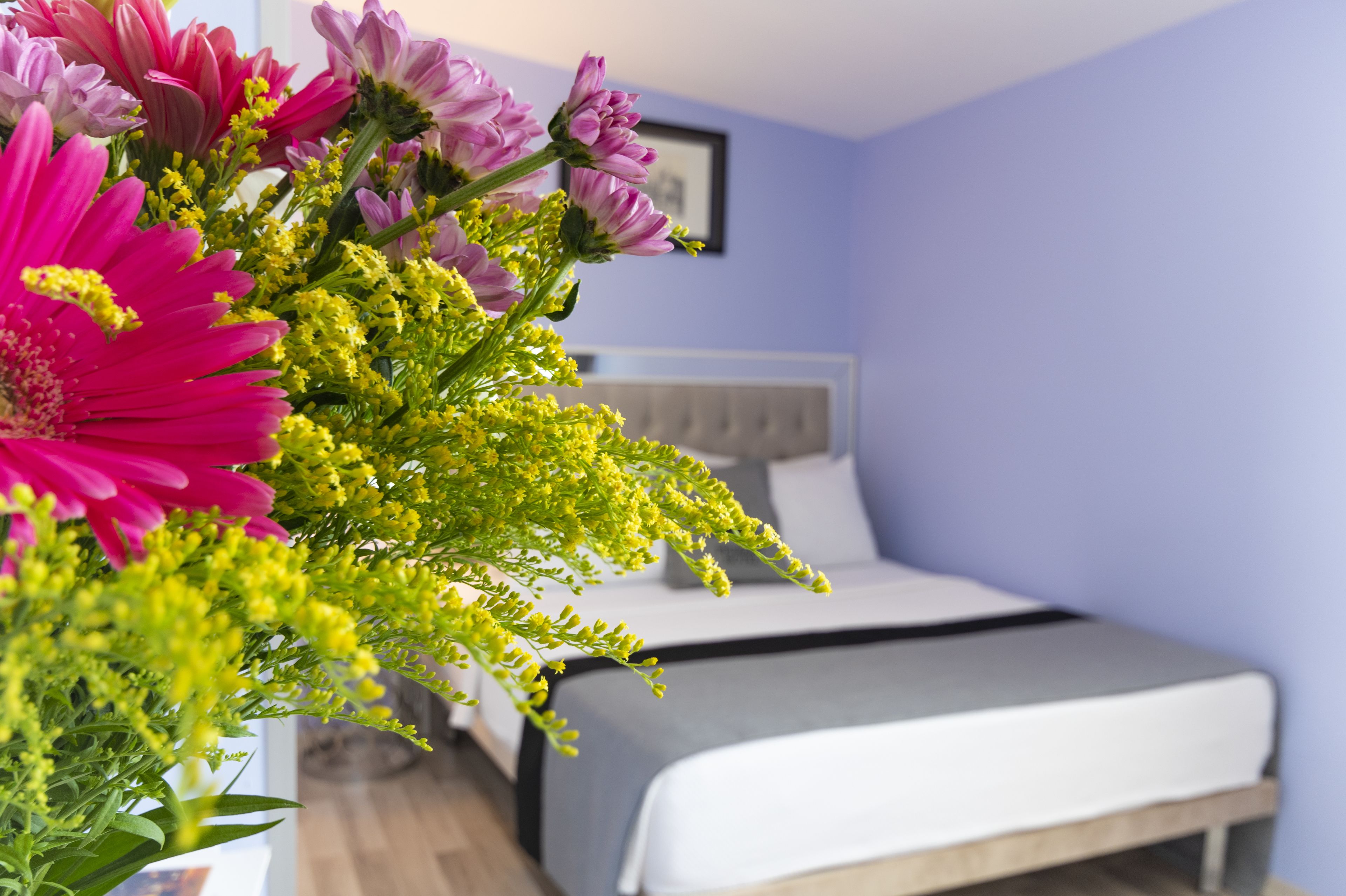 A bedroom with a bed, a nightstand, and a vase of flowers.