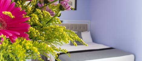 A bedroom with a bed, a nightstand, and a vase of flowers.