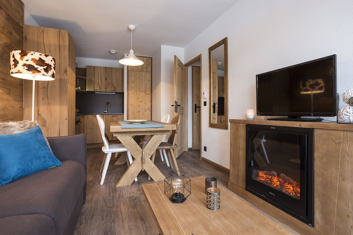 Een moderne woonkamer met een bank, een eettafel, een televisie en een open haard.