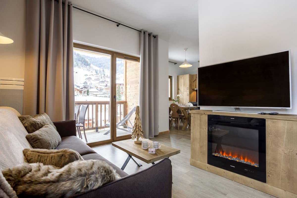 Een moderne woonkamer met een bank, een salontafel, een open haard en een televisie.
