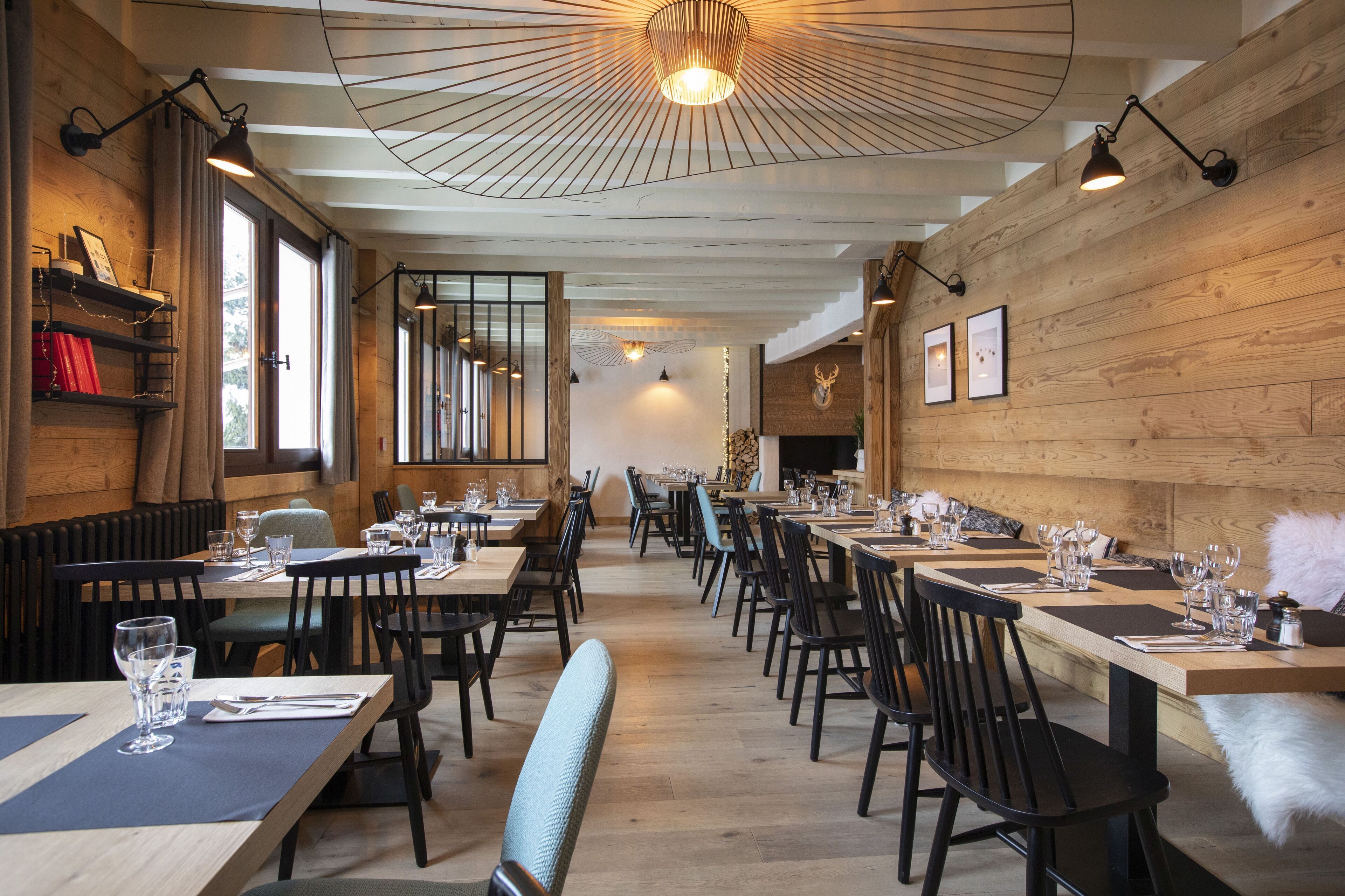 Un restaurant aux murs en bois, doté de nombreuses tables et de chaises noires.