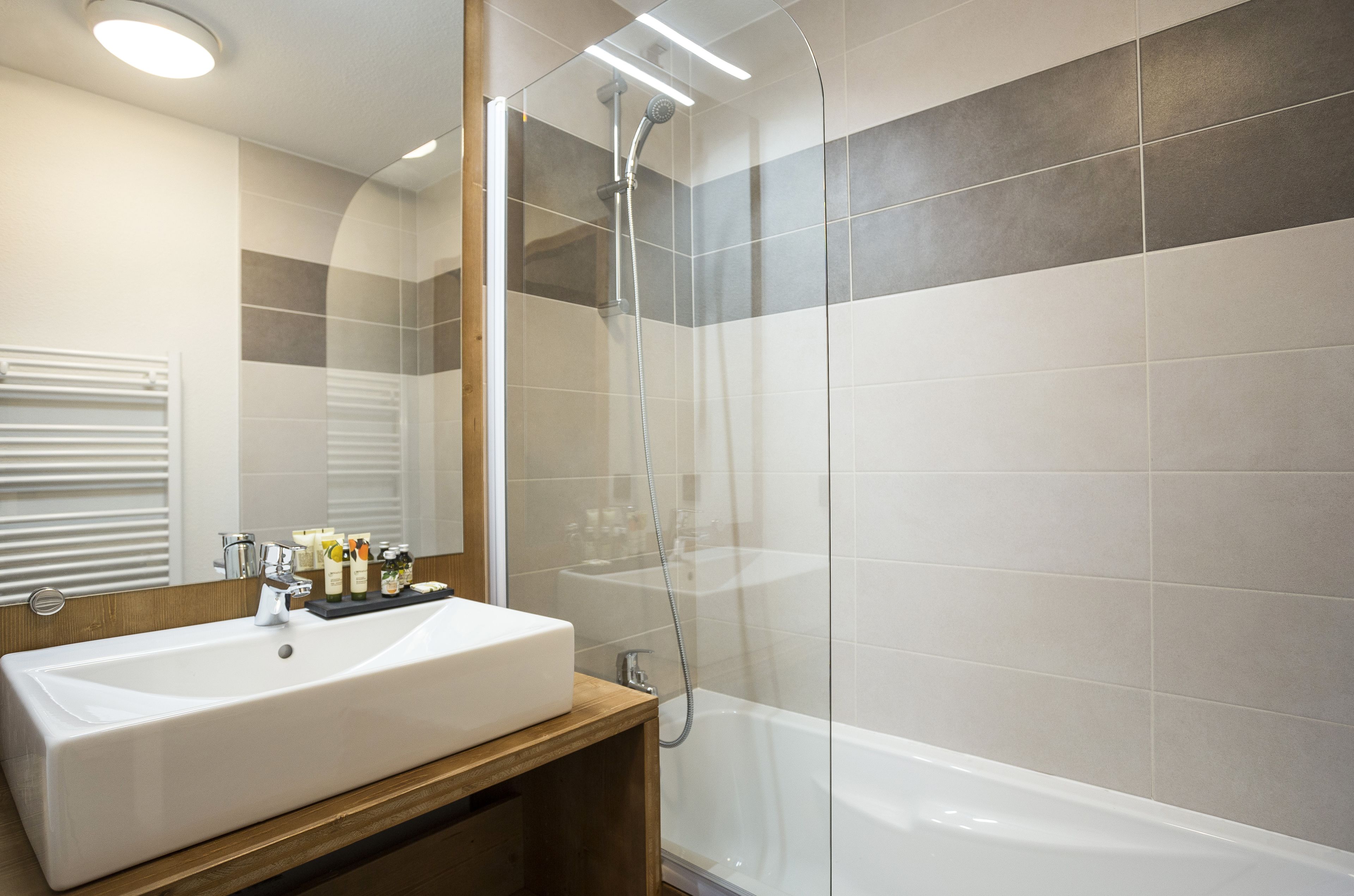 A modern bathroom with a large white sink, a glass-enclosed shower, and a mirror above the sink.