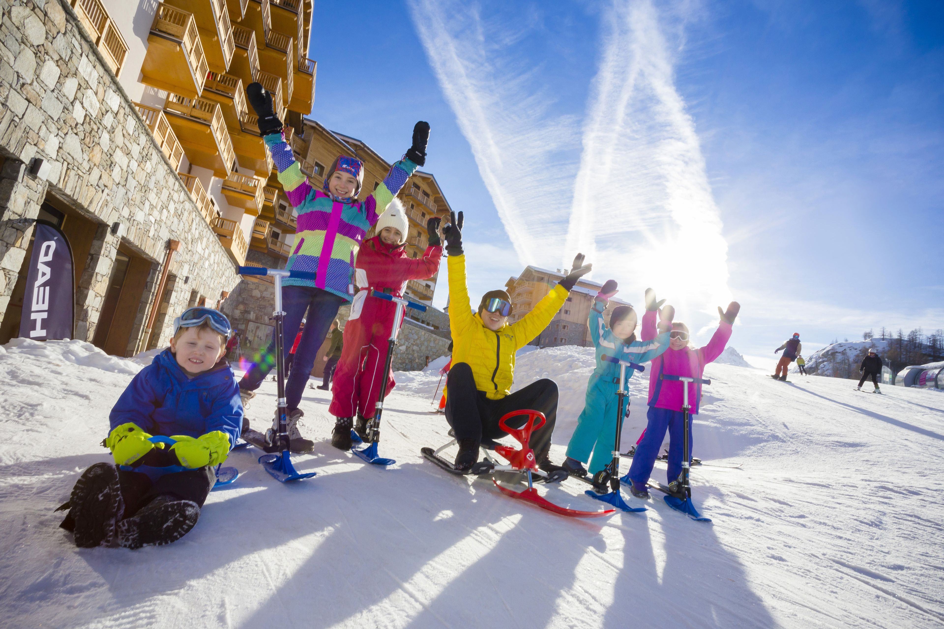 A group of people on a snowy slope with a stone building in the background.