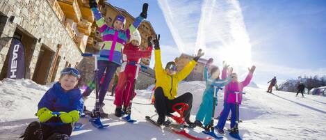 A group of people on a snowy slope with a stone building in the background.