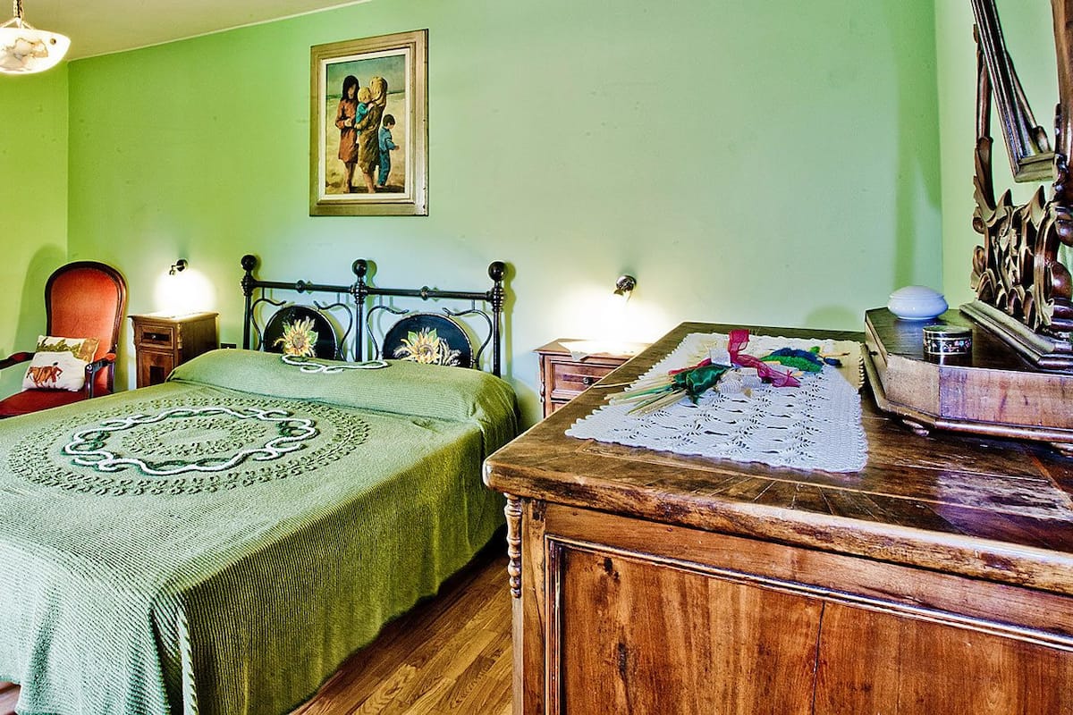 Ein Zimmer mit einem Bett, einem Holzschrank, einem Spiegel und einem Bild an der Wand.