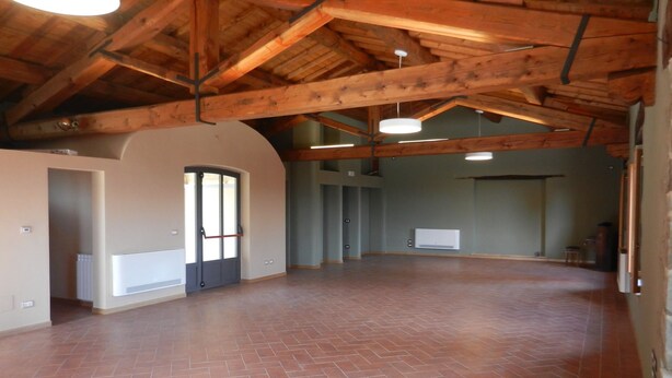 Ein geräumiges Zimmer mit hoher Decke und freiliegenden Holzbalken.