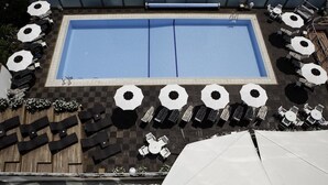 A rooftop pool area with multiple sun loungers and umbrellas, surrounded by a wooden deck and a checkered pattern floor. - Lido Hotel Residence (Cesenatico)