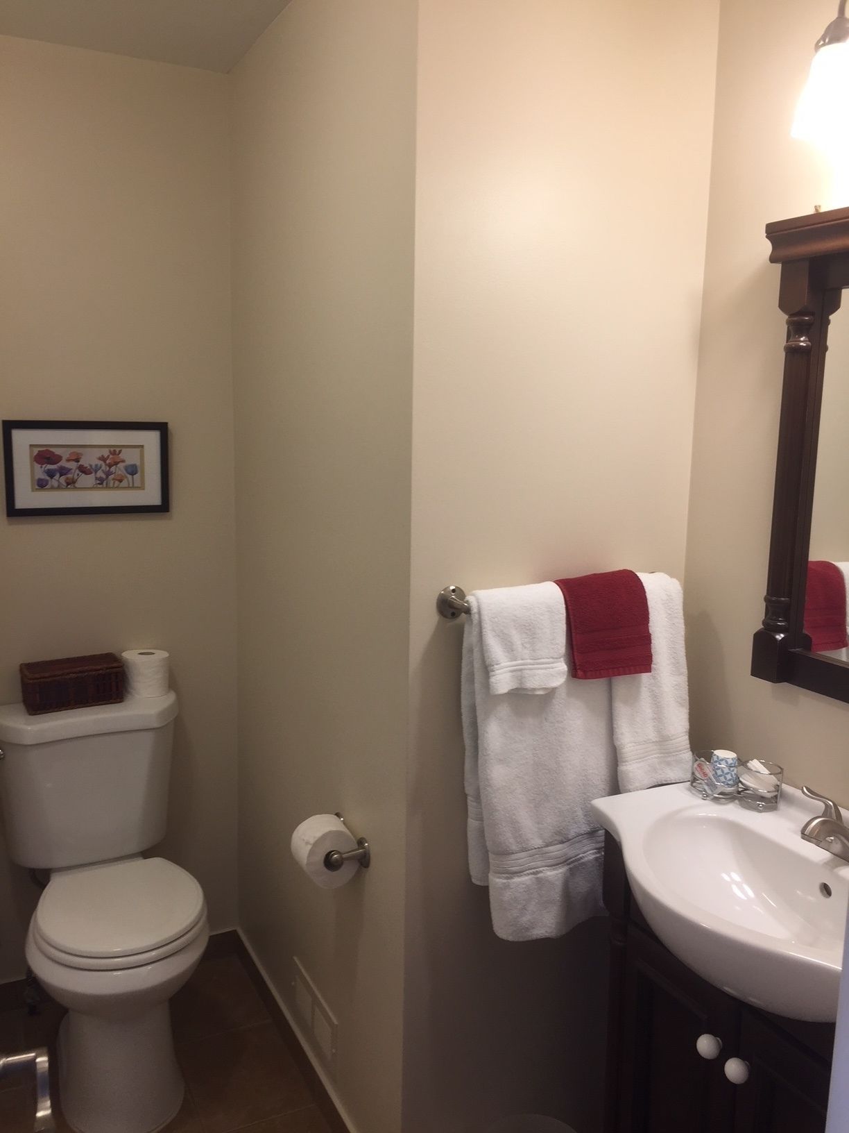 A bathroom with a toilet, sink, and a framed picture on the wall.