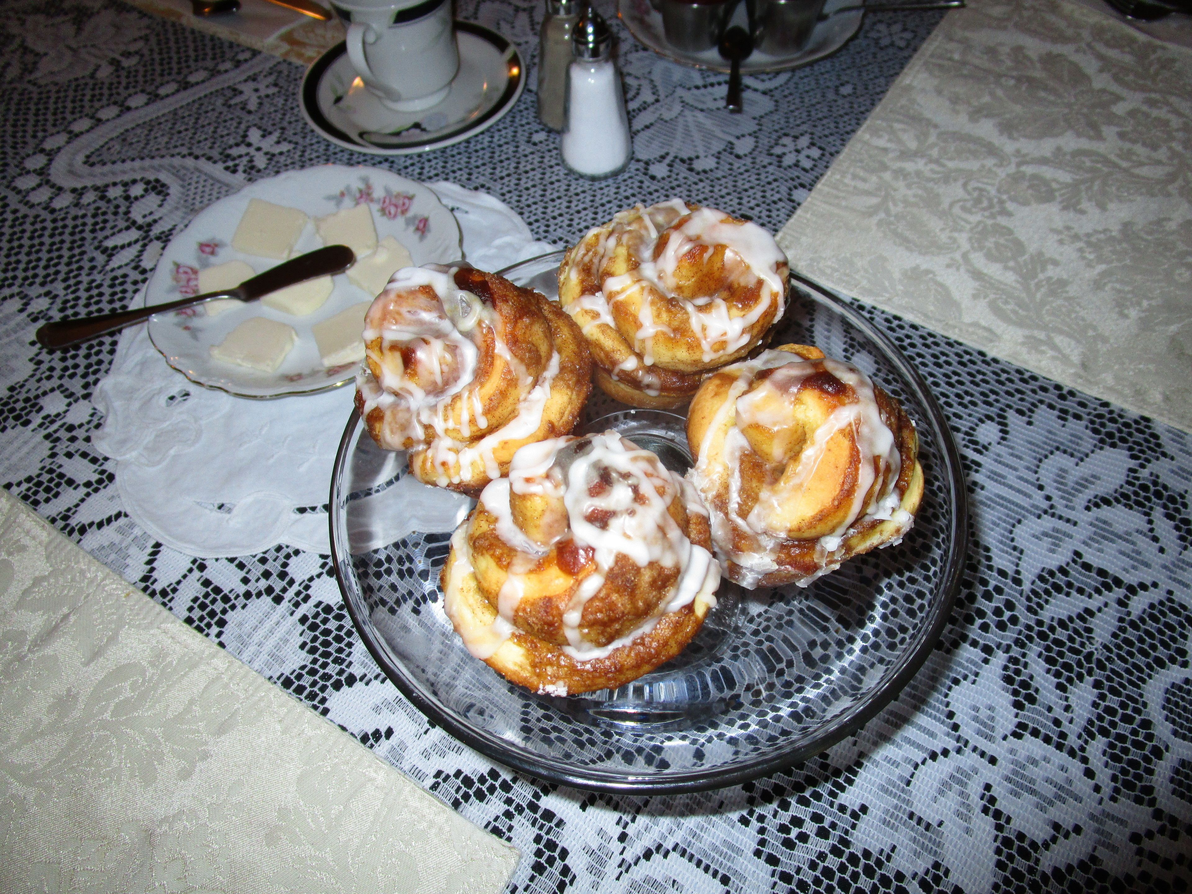 A plate of cinnamon rolls on a lace tablecloth.