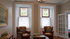 A room with two leather armchairs, a wooden coffee table, and a framed picture on the wall. - Sir Isaac Brock B&B Luxury Suites (Brockville)