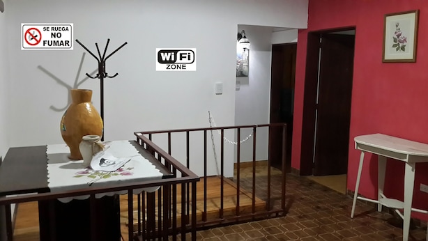 A room with a wooden railing, a vase, a table with a floral tablecloth, a WiFi sign, and a 'No Smoking' sign. - Departamento Palma 75 (Parana)