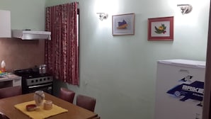 A compact kitchen with a stove, a refrigerator, and a dining table with chairs. - Departamento Palma 75 (Parana)