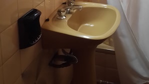 A bathroom with a beige sink, a towel rack, a toilet paper holder, and a shower curtain. - Departamento Palma 75 (Parana)