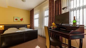 Habitación de hotel con cama, escritorio, silla, televisor y frutero.