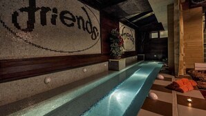 A spa area with a long, narrow pool, wooden benches, and a wall with the word 'friends' mosaic. - Hotel Friends (Bansko)