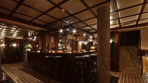 A bar area with a high ceiling, bar stools, and a patterned floor. - Hotel Friends (Bansko)