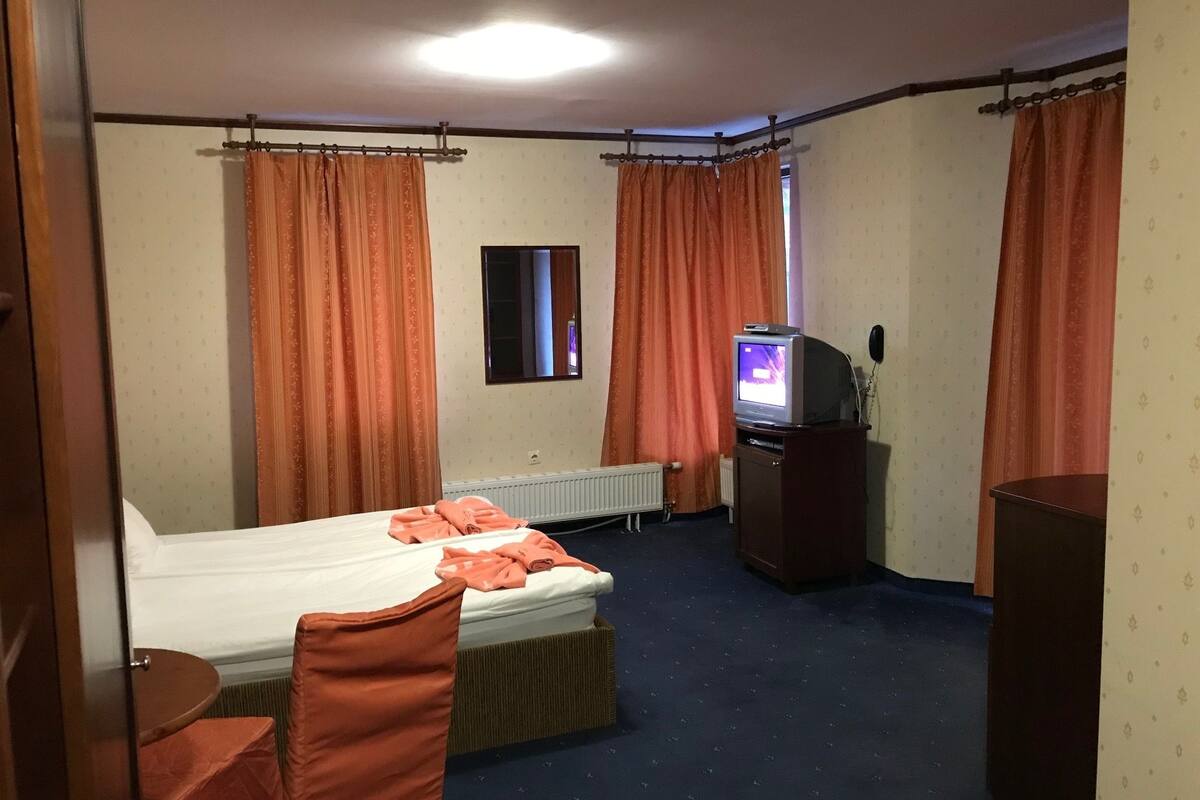 Ein Hotelzimmer mit Bett, Fernseher, Schreibtisch und Stuhl.