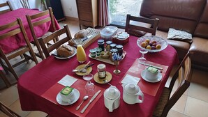 Una mesa de comedor lista para el desayuno, con pan, fruta y salsas.
