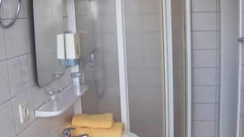Casa de banho com lavatório branco, espelho e cabine de duche.