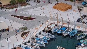 A marina with boats docked, a wooden platform, and a pedestrian walkway. - Murter Voltera (Tisno)