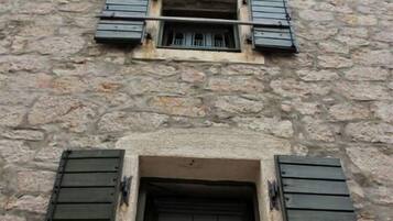 Un edificio in pietra con due finestre, ciascuna con persiane verdi.