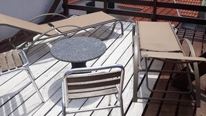 A terrace with a table and chairs, overlooking a body of water and a town with red-roofed buildings. - Murter Voltera (Tisno)