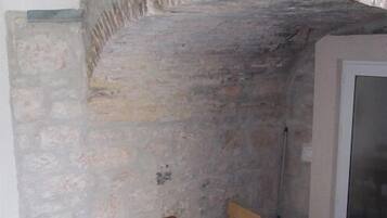 A room with a stone wall, a wooden table with chairs, and a door with a screen.