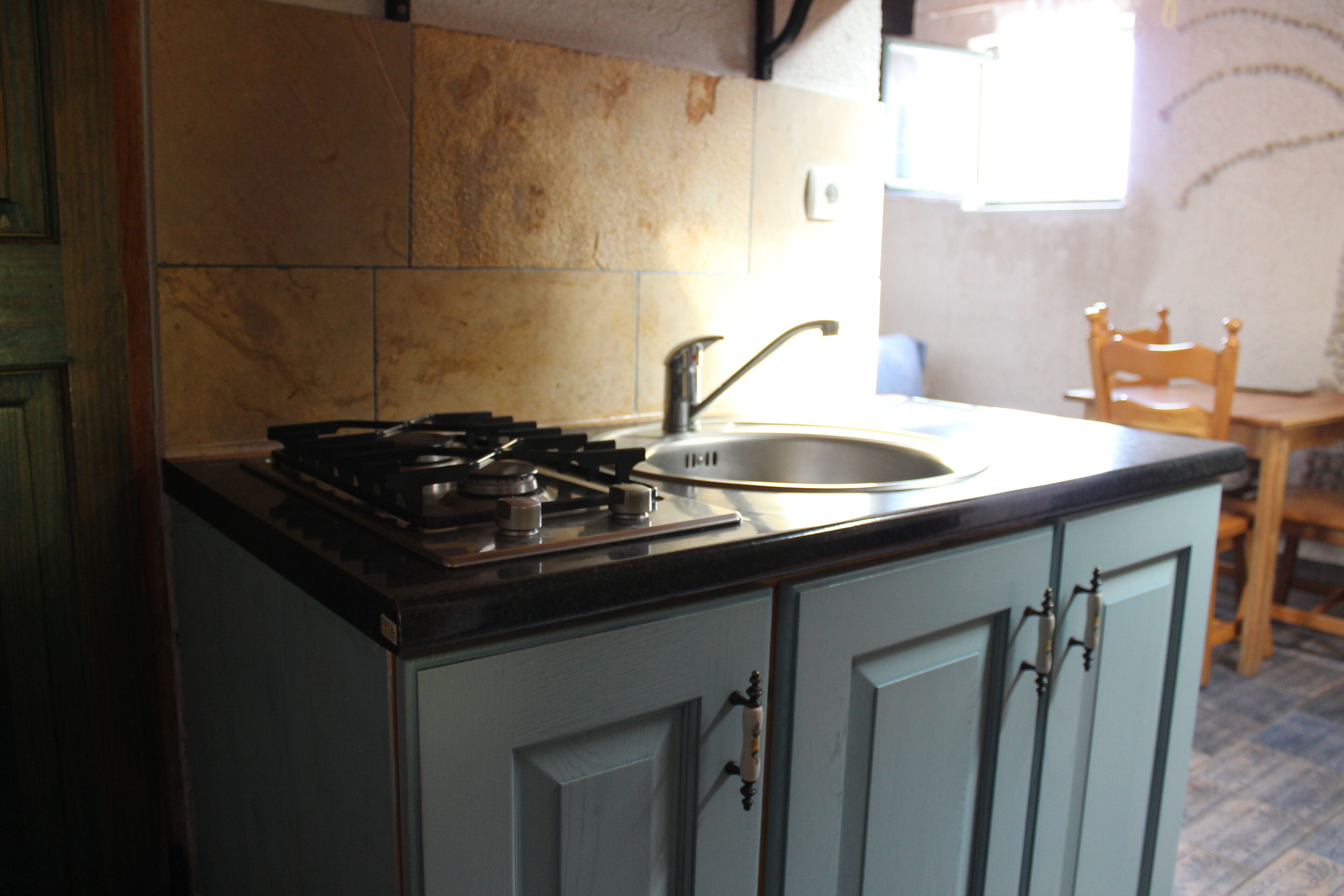 A kitchen with a gas stove, sink, and light blue cabinets.