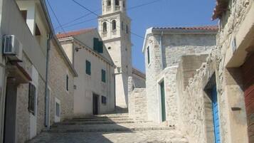 A narrow stone-paved street leading to a church with a red dome and bell tower.