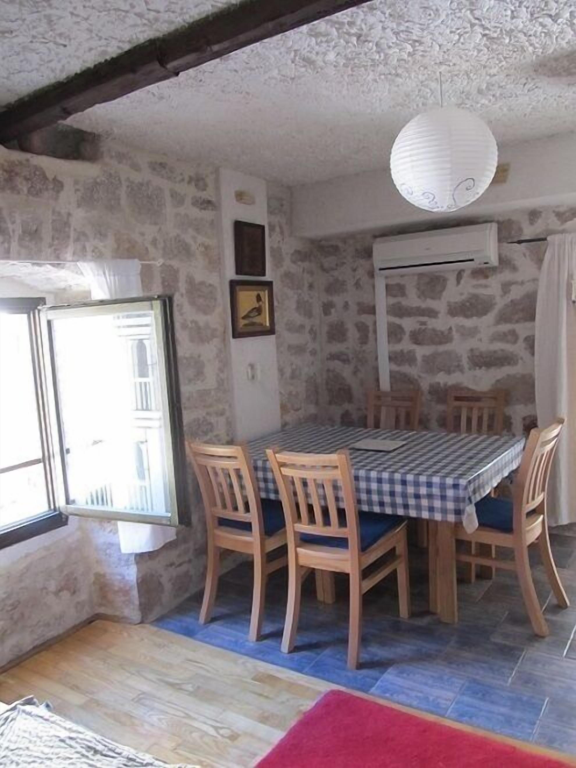 Un coin repas avec une table dressée pour quatre personnes, entourée de chaises en bois.