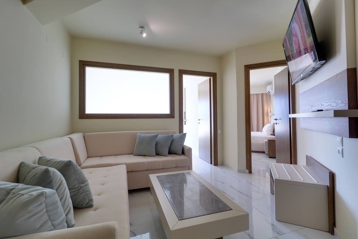 A modern living room with a sofa, a coffee table, and a TV mounted on the wall.