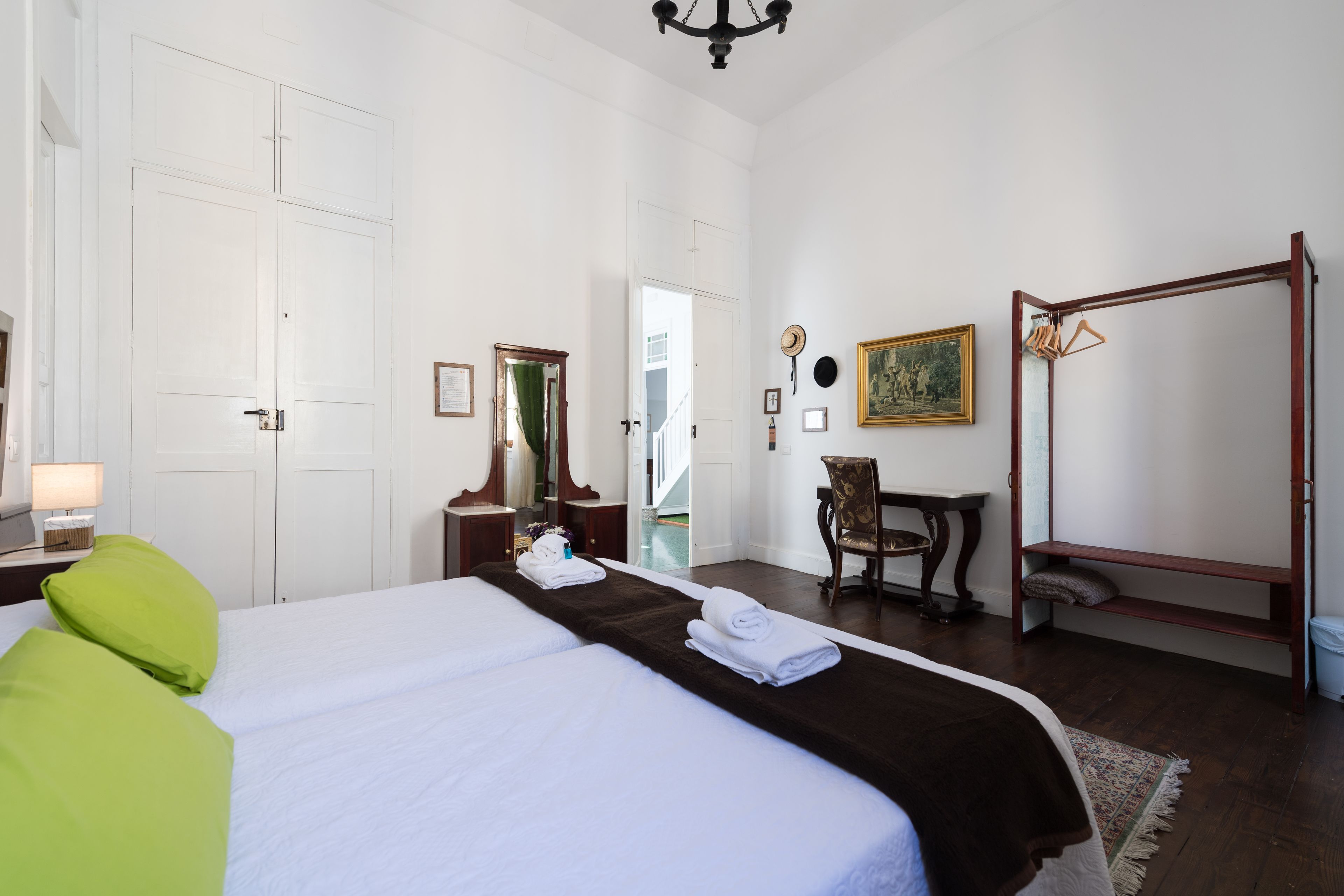 Une chambre d’hôtel avec un grand lit, une chaise en bois, une petite table et un fauteuil suspendu.