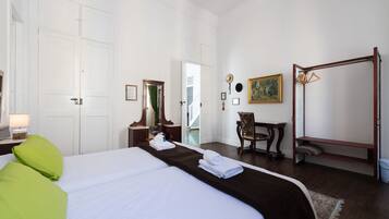 Une chambre d’hôtel avec un grand lit, une chaise en bois, une petite table et un fauteuil suspendu.