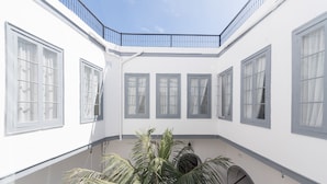 A white building with multiple windows and a central courtyard with a palm tree. - Casa Cinzia (Las Palmas de Gran Canaria)