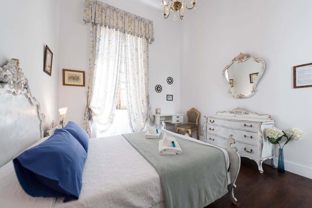 A bedroom with a bed, a dresser, a mirror, and a desk.