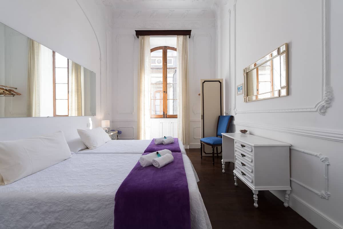 A hotel room with two beds, a dresser, a chair, and a large mirror.
